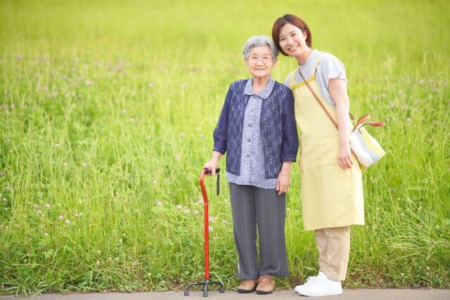 杖をもつ高齢女性と介護士の女性