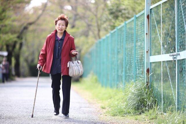 杖をついて歩く高齢女性