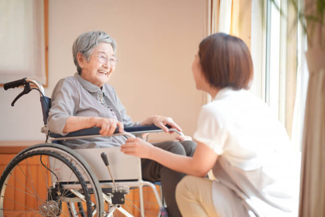 車椅子の女性と話す介護士